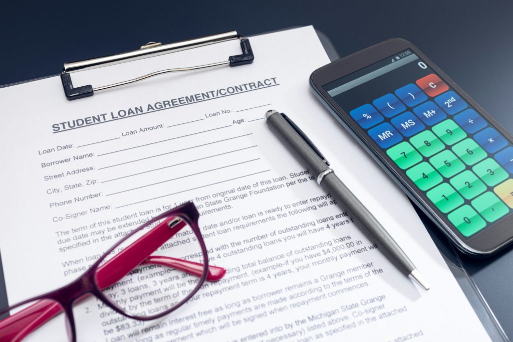 Student Loan Application, calculator, pen and eyeglasses on table